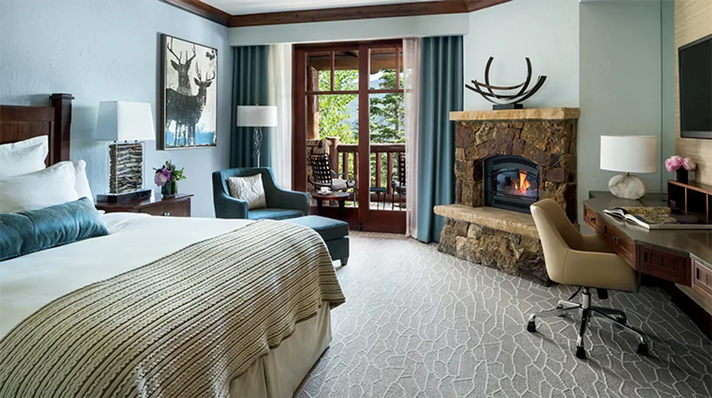 Cozy bedroom at The Ritz-Carlton, Bachelor Gulch in Aspen, featuring a fireplace and balcony.